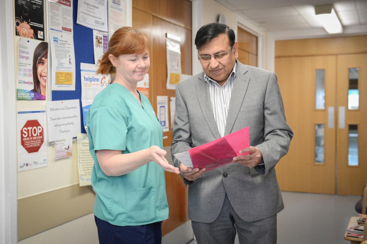 Two NHS staff conversing and looking at a folder